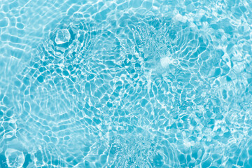 Blue water with ripples on the surface. Defocus blurred transparent blue colored clear calm water surface texture with splashes and bubbles. Water waves with shining pattern texture background.