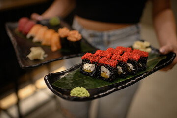 sushi and rolls in the hands of a girl on plates. beautiful presentation of Japanese food waiter