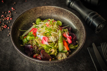 A vibrant salad with fresh vegetables, microgreens, cucumber ribbons