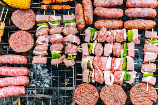 cooking meat on barbecue grill at bbq party in summer garden &ndash; shashlik or shish kebab prepared on arbecue grill over hot charcoal grilled vegetables 