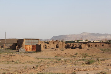 Old rural buildings in a desert environment under a clear sky, evoking a sense of historical isolation and rustic charm.