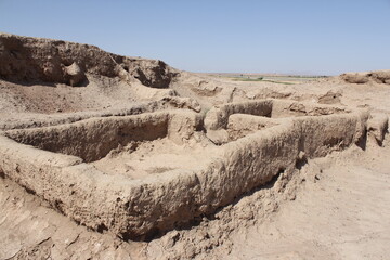Obraz premium Archaeological site with excavated stone walls, revealing ancient architecture and historical ruins in a vast open area.