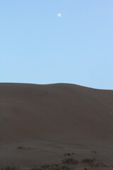 A crescent moon hanging over the desert dunes, adding a mystical touch to the quiet night.