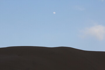 Majestic desert dunes at dusk with a darkening sky, emphasizing the tranquil isolation of the desert.