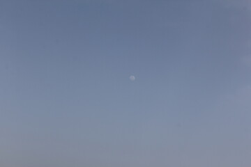 A crescent moon above the desert horizon in twilight, creating a peaceful, dreamlike scene.