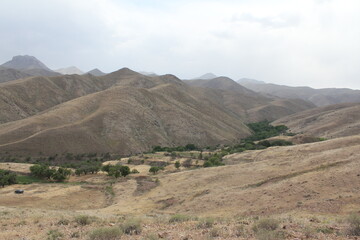 Stone ruins and ancient structures scattered in a dry, mountainous landscape under the open sky.