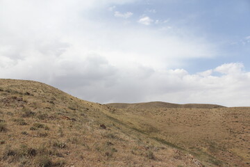 Dry hills and rugged terrain stretching across the landscape under a cloudy sky.