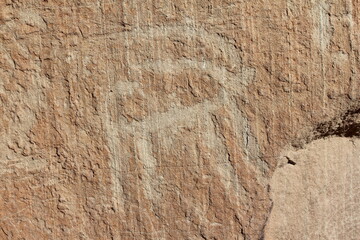 Large stone engravings on an ancient rock face in an isolated, rugged desert landscape.