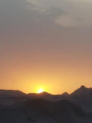 A desert landscape with rugged rock formations and clear blue sky, showcasing the harsh yet stunning beauty of arid regions.