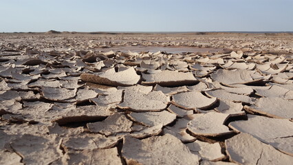A wide view of cracked desert terrain with dramatic soil patterns, highlighting the harsh and rugged beauty of untouched arid landscapes.