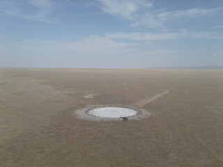 A salt flat with circular patterns and textures under the clear sky, demonstrating geological uniqueness and minimalistic beauty in nature.