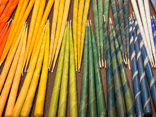 Handmade candles arranged in sets of three, with a smooth color gradient from red to yellow, green, and blue