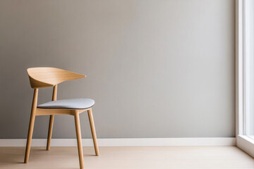 Modern wooden chair placed against a plain wall near a large window providing natural light