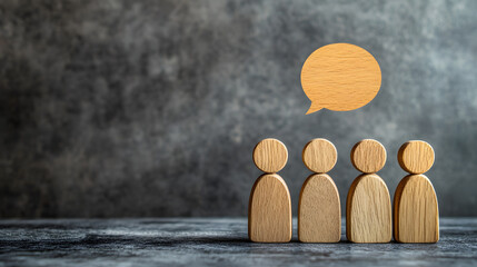 Four wooden figurines standing together with a speech bubble above, symbolizing communication, teamwork, or group discussion.