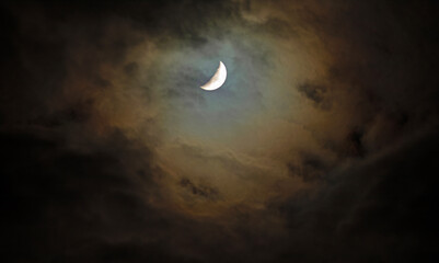 Fototapeta premium Warm glow of the moon through an opening in the clouds