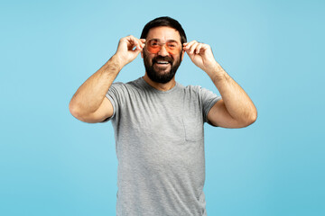 Naklejka premium Handsome bearded man wearing stylish sunglasses and smiling on blue background