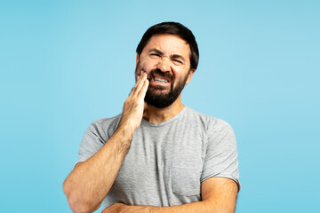 Man experiencing severe toothache on blue background