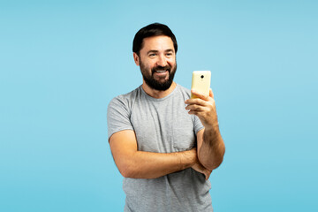 Happy bearded man using smartphone on blue background