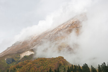 Part of the Mount Oshten covered with a thick fog and clouds in autumn, Russian Federation