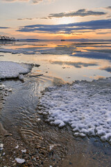  Winter landscape. The surface of the ice is bound by ice, with a perfectly smooth, mirror-like appearance. Sunset in winter over the lake. 