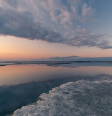 Obraz premium Winter landscape. The surface of the ice is bound by ice, with a perfectly smooth, mirror-like appearance. Sunset in winter over the lake. 