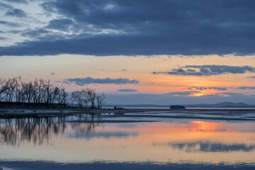  Winter landscape. The surface of the ice is bound by ice, with a perfectly smooth, mirror-like appearance. Sunset in winter over the lake. 