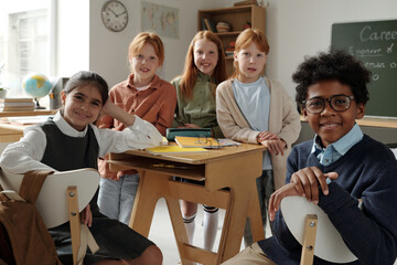 Group of cheerful and diligent schoolgirls and schoolboy looking at camera in classroom on career day at break