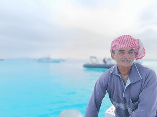 Fototapeta premium an old sailor with a white mustache who is a retired soldier in the navy wearing a Bedouin scarf on his head