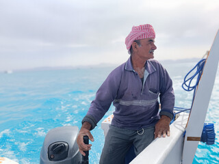 Old Sailor in the Sea Riding and Sailing with his Boat An old sailor with a white with a white mustache who is wearing a Bedouin Scarf on his head