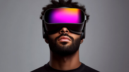 Young man wearing a colorful AR headset, gazing upward against a gray background. Concept of futuristic technology. For technology ads