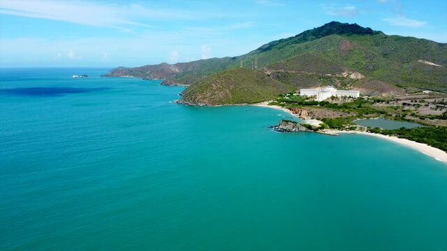 A beautiful beach with a blue ocean and a mountain in the background. The beach is empty and the water is calm
