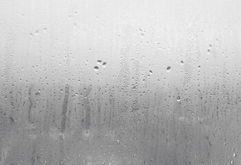 Foggy glass with raindrops sliding down