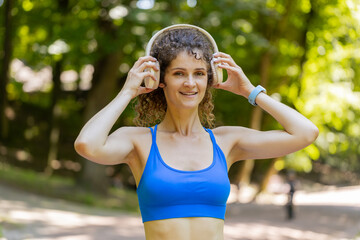 Portrait of athletic fitness sport runner girl training, putting on wireless headphones and listening favorite music song. Workout cardio in morning park. Young woman jogger enjoy healthy lifestyle.