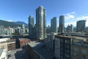 Fototapeta premium A panoramic view of a modern city skyline with tall skyscrapers and snow-capped mountains in the distance.