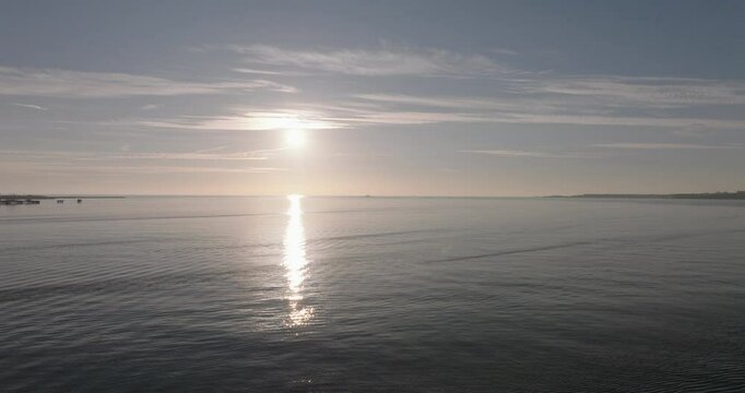 Aerial drone shot flying towards the Atlantic Ocean and horizon at sunset from Lisbon, Portugal, Europe. Drone flying towards the Forte do Bugio lighthouse during golden hour. Shot in ProRes 422 HQ