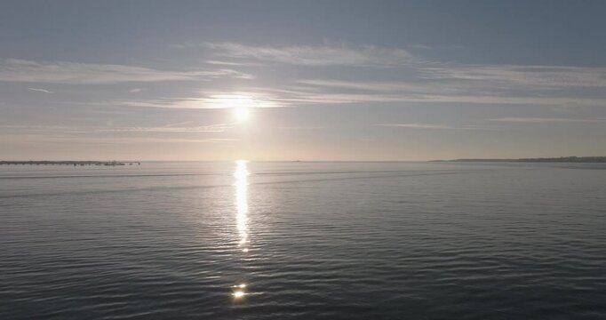 Aerial drone shot flying towards the Atlantic Ocean and horizon at sunset from Lisbon, Portugal, Europe. Drone flying towards the Forte do Bugio lighthouse during golden hour. Shot in ProRes 422 HQ