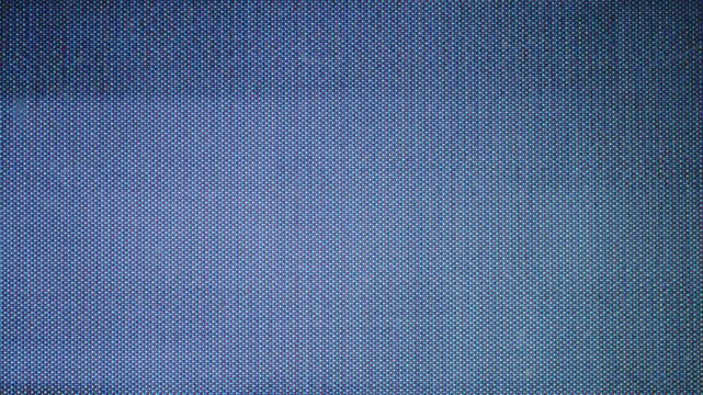 A close-up of the texture of LED screen material, with small dots and a dark blue color background. The pattern is symmetrical and uniform in size, with bright light shining on it from above. 4k.