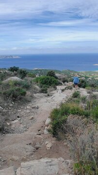 Handheld view of a woman and dog descending from the abandoned historic ruin village of Occi