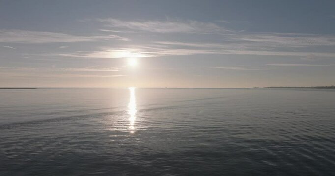 Aerial drone shot flying towards the Atlantic Ocean and horizon at sunset from Lisbon, Portugal, Europe. Drone flying towards the Forte do Bugio lighthouse during golden hour. Shot in ProRes 422 HQ