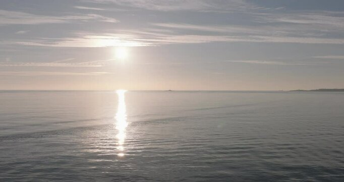 Aerial drone shot flying towards the Atlantic Ocean and horizon at sunset from Lisbon, Portugal, Europe. Drone flying towards the Forte do Bugio lighthouse during golden hour. Shot in ProRes 422 HQ
