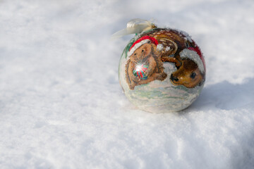 Christmas card. Christmas bauble with fairy motif lying on natural snow on a frosty sunny day.