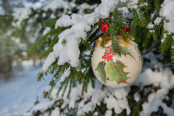 Christmas bauble hanging on a Christmas tree covered in snow