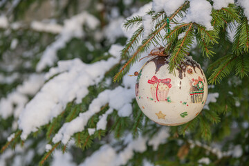 Christmas bauble hanging on a Christmas tree covered in snow