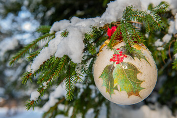 Christmas bauble hanging on a Christmas tree covered in snow