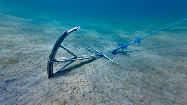 Anchor on the seabed. A metal anchor lies on the sandy seabed, buried in the ground.
