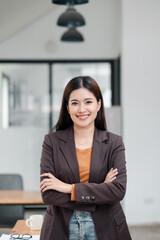 Confident Young Professional Woman Smiling in Modern Office Environment with Arms Crossed