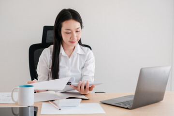 Professional Woman Working at Desk with Laptop and Documents in Modern Office Setting