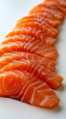 Close-up of fresh salmon sashimi arranged in a row on a white background. The salmon is sliced thinly and has a beautiful orange color.