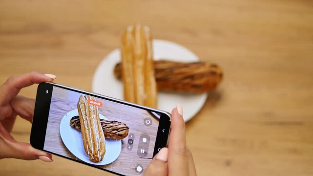 Woman capturing dessert on mobile phone, focusing on perfect shot. Creative process highlights artistic approach to food photography. Ideal for themes of food, snapshots, and creative dessert shots.