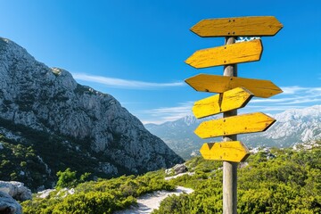 A signpost with multiple yellow arrows in a mountainous landscape under a blue sky.